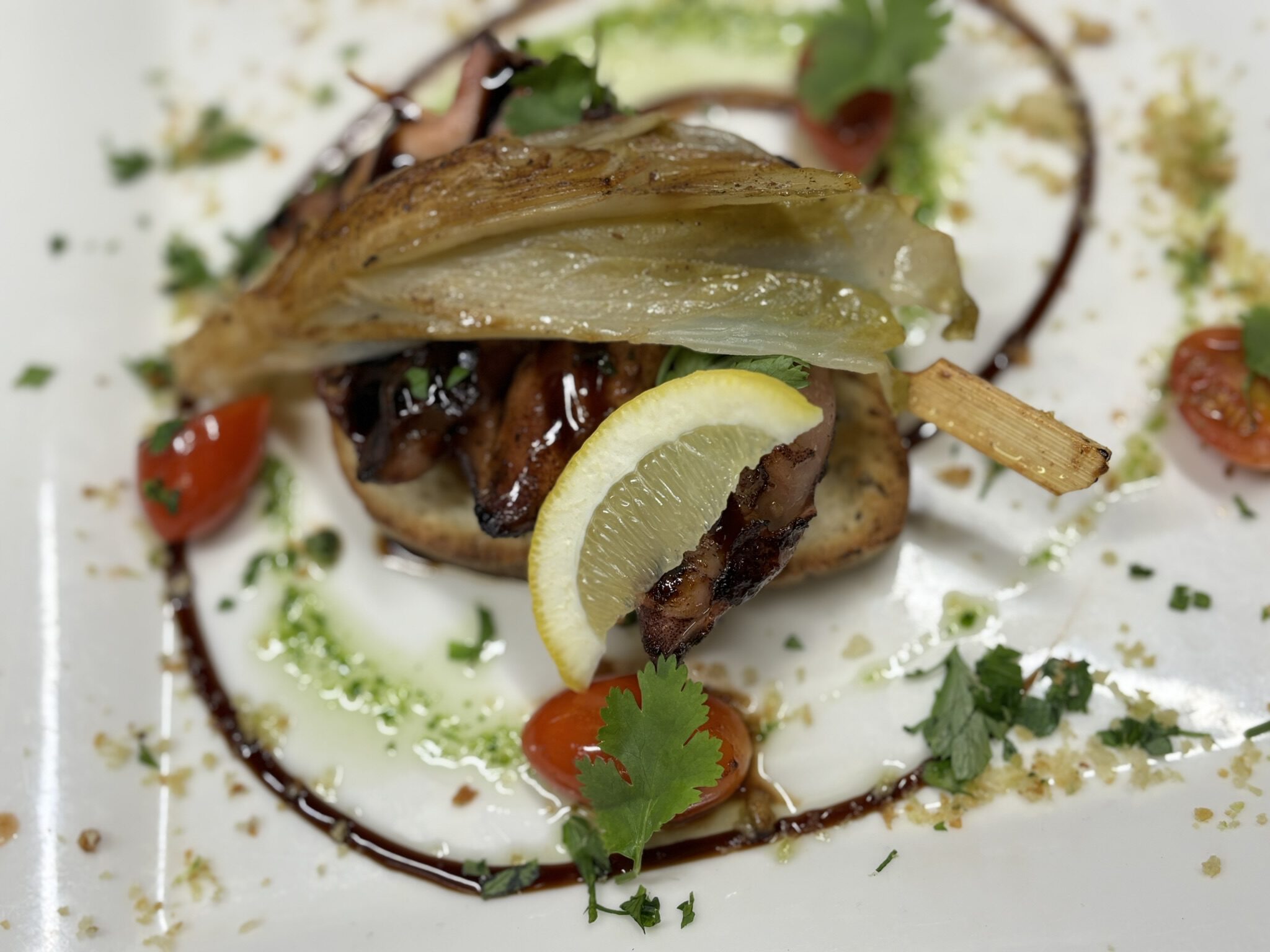 bord met inktvis, gegarneerd cherrytomaatjes en limoen